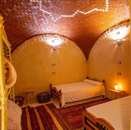 锡瓦Siwa Palace Lodge的一间设有两张床和砖墙的房间