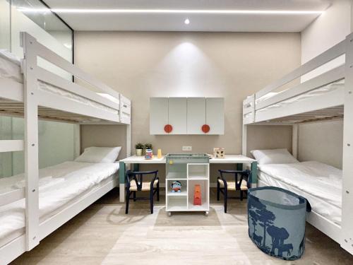 乔治市Designer Guesthouse Pulau Tikus & Gurney Drive, Georgetown, Penang的客房设有两张双层床和一张桌子及椅子。