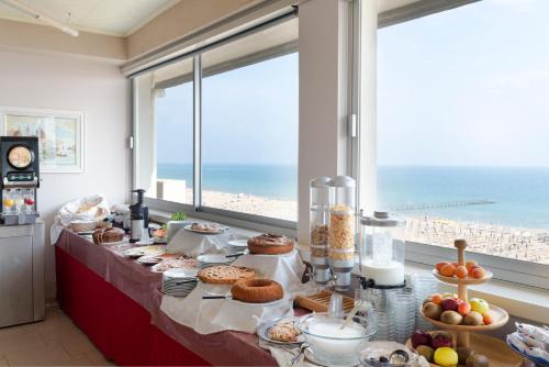 里米尼Hotel Centrale Miramare的一张带食物的桌子,享有海滩美景