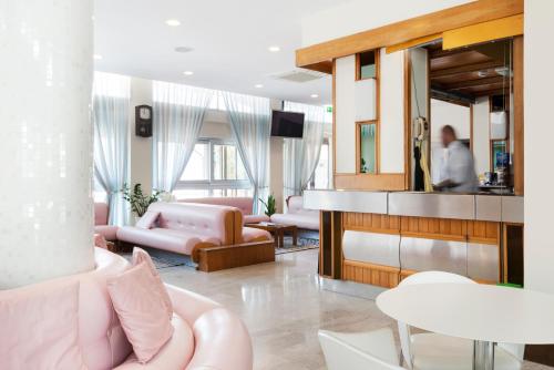里米尼Hotel Centrale Miramare的客厅配有粉色家具,镜子里还有人