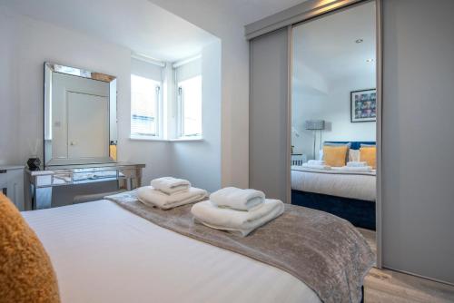 伦敦2 Bed town house with Garden in Hackney, London的一间卧室,在床上配有两张毛巾和镜子