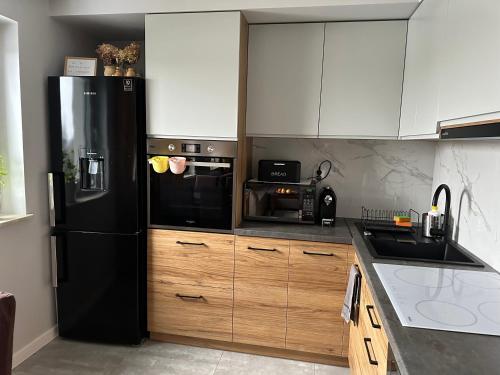 海乌姆Apartament z widokiem的厨房配有黑色冰箱和木制橱柜。