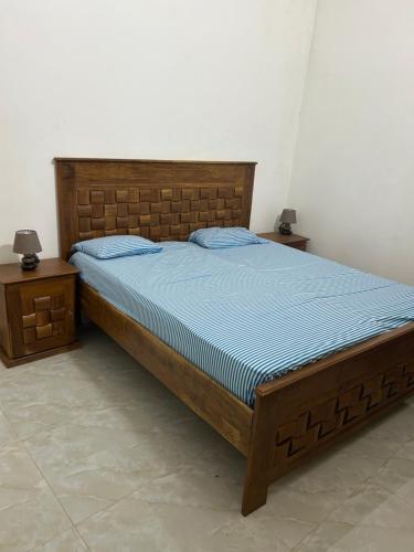 RufisqueVilla Kayus - Toubab Dialaw的一间卧室配有一张带蓝色棉被的床和两张桌子