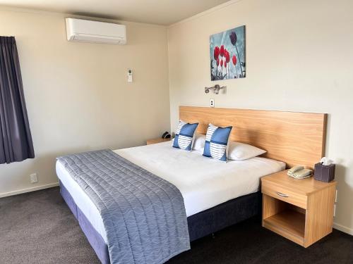 纳尔逊阿卡迪亚汽车旅馆的一间卧室配有一张大床和木制床头板