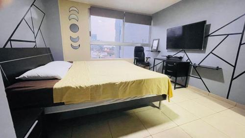 瓜亚基尔Five Stars Suites - Kennedy - Guayaquil的一间卧室配有一张床、一张书桌和一台电视