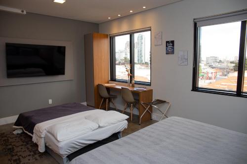 圣保罗Flat Tatuapé Sua Casa Your Home的一间卧室设有两张床、一张桌子和窗户。