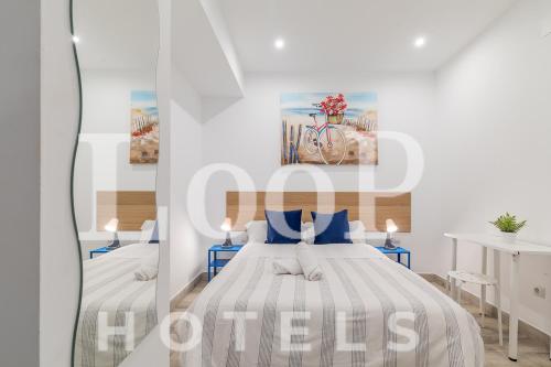 马德里LooP Las Ventas的白色卧室配有两张带蓝色枕头的床