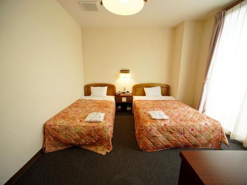 ShinkamigotoHOTEL MARINEPIA - Vacation STAY 92240v的酒店客房设有两张床和一张桌子。