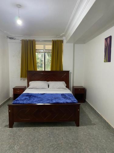 NamugongoIngrid's Place - Namugongo的一间卧室配有一张带蓝色棉被的床和窗户。