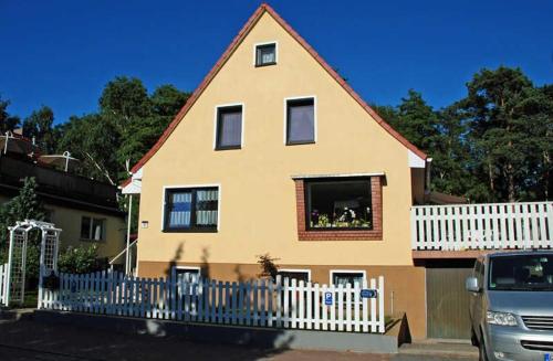 巴贝Ferienwohnung zur Baaber Heide的黄色房子,有白色的栅栏和面包车