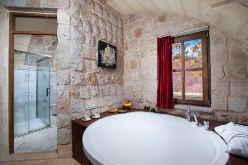 乌奇希萨尔Woox Cappadocia的石质浴室设有大型白色浴缸,浴室设有窗户