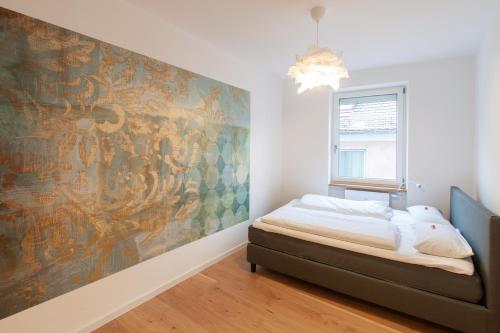 维尔茨堡Juliusliving - modernes Wohnen an der Juliuspromenade的卧室配有一张床,墙上挂有绘画作品