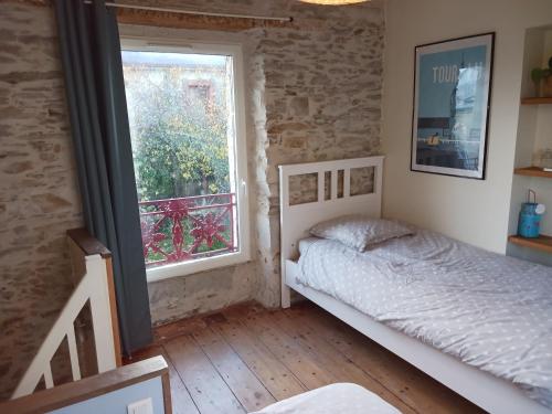 南特Le pigeonnier de la plume的一间卧室设有一张床和一个窗口