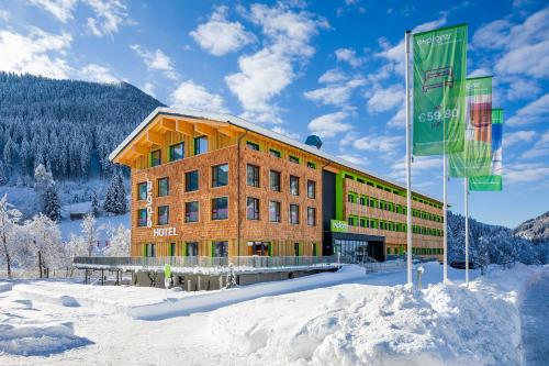 巴德小基希海姆Explorer Hotel Bad Kleinkirchheim的雪上有两面旗帜的建筑