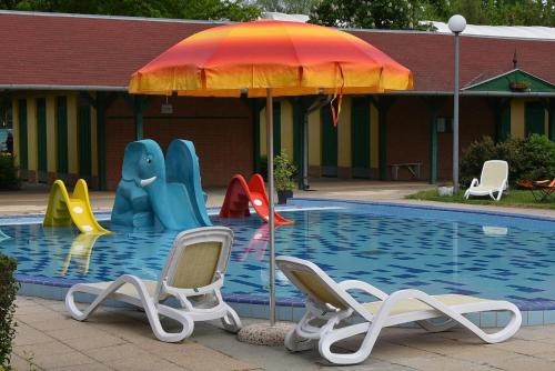 森特什Szentesi Sport- és Üdülőközpont的游泳池旁的游泳池配有椅子和遮阳伞