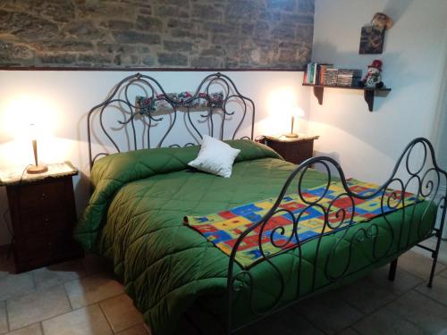 卡普拉科塔La tana delle coccinelle的一间卧室配有一张带两盏灯的绿床。