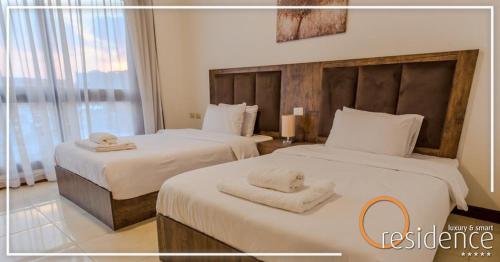 开罗luxury apartments in cairo , porto new cairo , nyum的两张位于酒店客房的床,配有毛巾