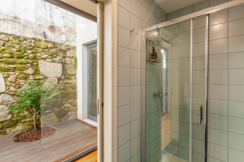 布拉加Yellow Lodge - Minho's Guest的石墙浴室内的玻璃淋浴间