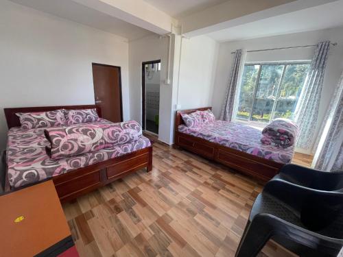 大吉岭Jasmine Homestay Darjeeling的一间卧室设有两张床和窗户。
