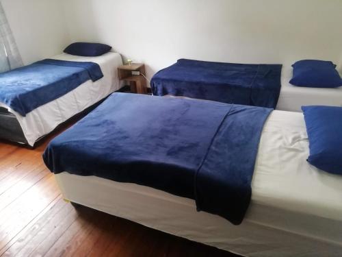 德班PHAKADEHOMES的客房内的三张床,配有蓝色床单