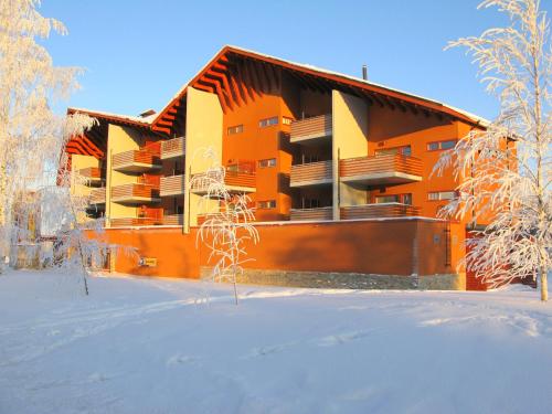 塔库沃里Apartments Tähtitahko的一座橘色的公寓楼,位于雪地里,树木繁茂