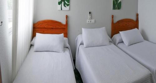 La GuijarrosaHostal Al-Andalus的白色墙壁客房中的两张单人床