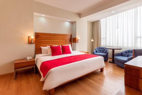 波拉马尔Hotel Faranda Express Puerta del Sol Porlamar的酒店客房配有一张带红色枕头的大床