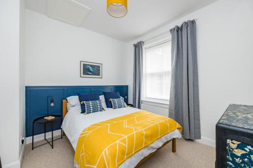 HurstpierpointAscot House Apartment的一间卧室设有黄色和蓝色的床和窗户。