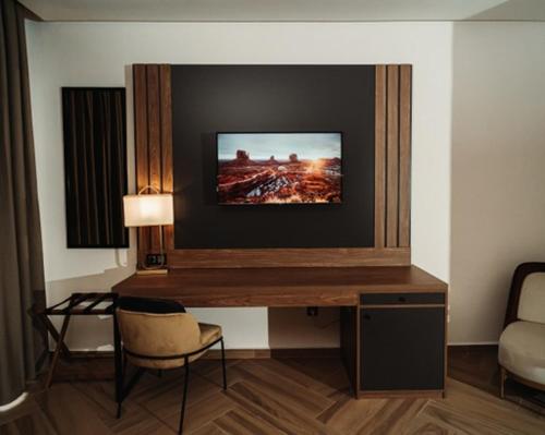 盖尼特拉City Hotel by Waves的一间设有一张桌子的房间,墙上配有电视