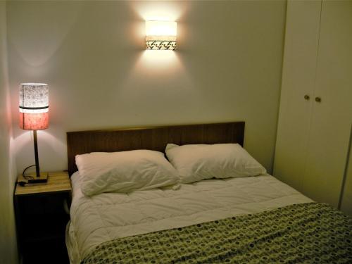 勒帕莱Appartement Le Palais, 2 pièces, 3 personnes - FR-1-418-230的卧室配有一张墙壁上灯床。