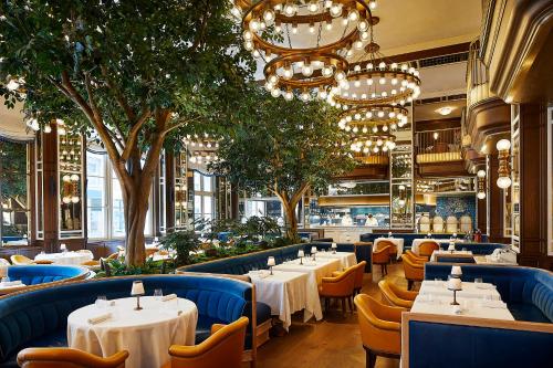 纽约The Fifth Avenue Hotel的一间设有白色桌椅和树木的餐厅