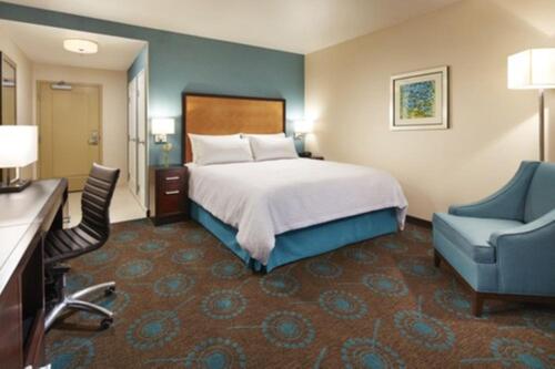 圣地亚哥圣地亚哥大使谷汉普顿酒店的酒店客房,配有一张床和一张蓝色椅子