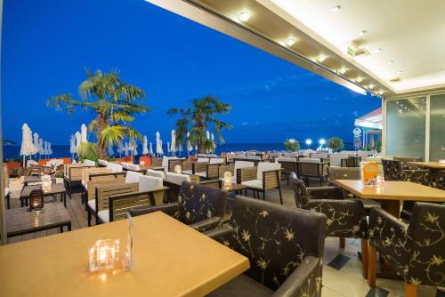 帕拉利亚卡泰里尼斯全景酒店的餐厅设有桌椅,以大海为背景