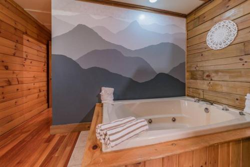 鸽子谷Couples Getaway Cabin near National Park w Hot Tub的配有山壁画的客房内的浴缸
