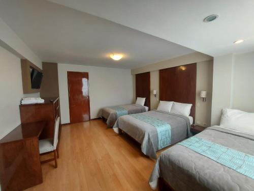 塔克纳Miculla Hotel的酒店客房配有两张床和一张书桌