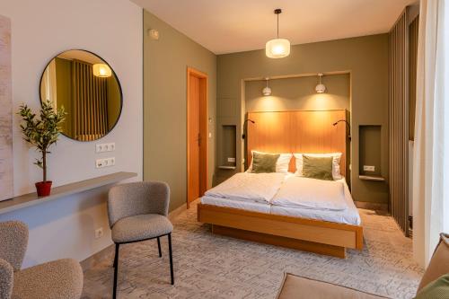 魏玛Hotel Erbenhof的一间卧室配有一张床、镜子和椅子
