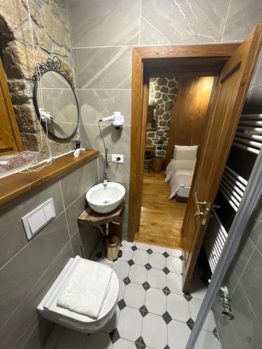 沃斯科波亚Hotel Ambassador Voskopojë的一间带水槽、卫生间和镜子的浴室