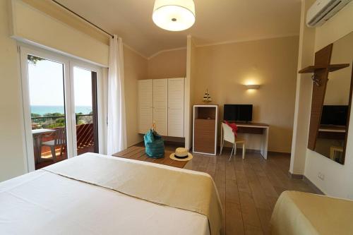 克罗托内hotel villaggio Casarossa的一间卧室配有一张床、一张书桌和一台电视