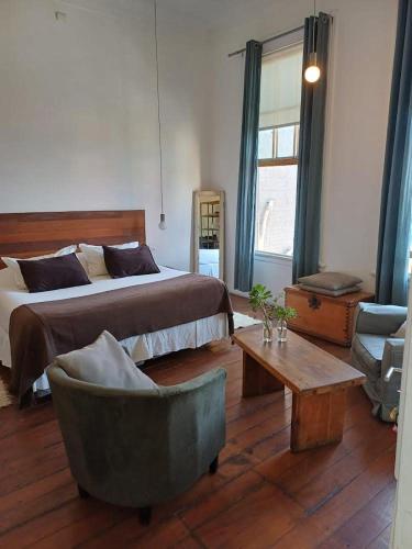 瓦尔帕莱索Apartamentos Cerro Alegre的一间卧室配有一张床、一把椅子和一张桌子