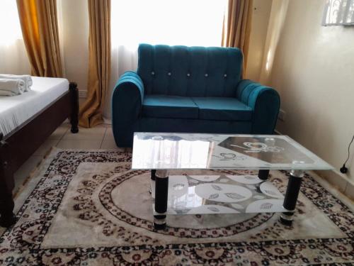 蒙巴萨Galene Abode Studio Apartment, Nyali的客厅配有蓝色的沙发和玻璃咖啡桌