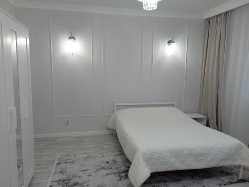 阿斯塔纳1-но комнатная квартира в центре Астаны ЖК Sezim Qala 4的白色卧室配有一张床和墙上的两盏灯
