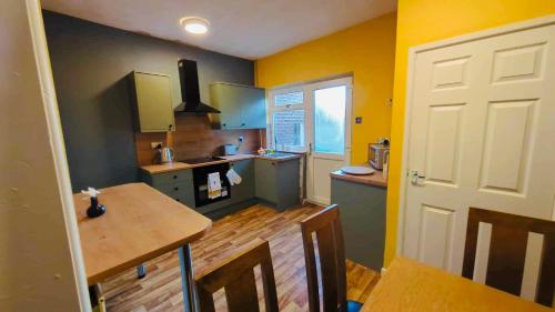威根The Smart Stay - sleeps 5 Wigan central location的厨房设有黄色的墙壁和木桌