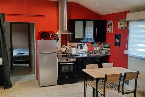 圣迪济耶charmante maison de ville的厨房设有红色的墙壁、桌子和冰箱