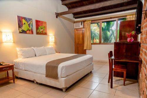 塔拉波托DM Hoteles Tarapoto的一间卧室配有一张床、一张书桌和一个窗户。