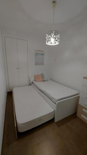 阿桂拉斯Apartamento moderno vacacional的白色卧室配有一张床和一个吊灯