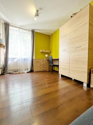 克拉科夫Cosy room Aleja Kijowska的一间空客厅,铺有木地板,拥有黄色的墙壁