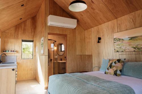 比舍诺Bicheno Garden Cottages的一间带木墙的卧室和一张位于客房内的床