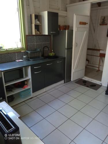 勒弗朗索瓦Le Bungalow des Hauts de la Prairie的带冰箱的厨房和瓷砖地板。