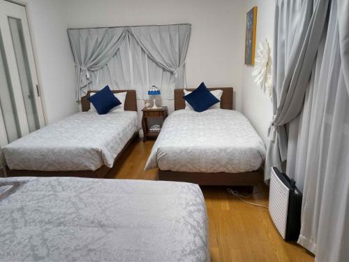 直岛町Yellow House的一间卧室配有两张带蓝色枕头的床