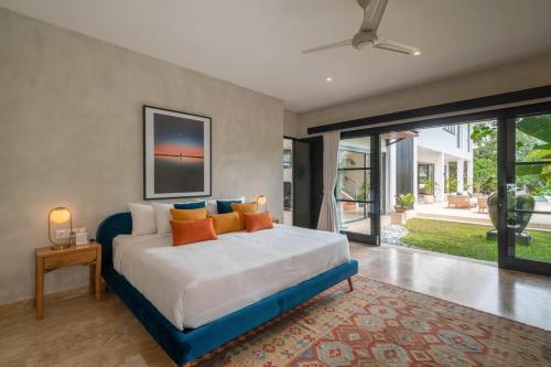 MungguCemagi Beachside Sultana: 5BR Luxury Villa Canggu的一间卧室配有一张带橙色和蓝色枕头的大床